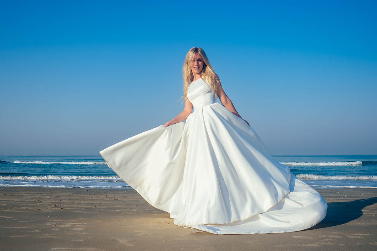 Schöne und glückliche Braut in einem schicken langen weißen Hochzeitskleid wirbelt und tanzt am Strand. auf der Insel Ruegen