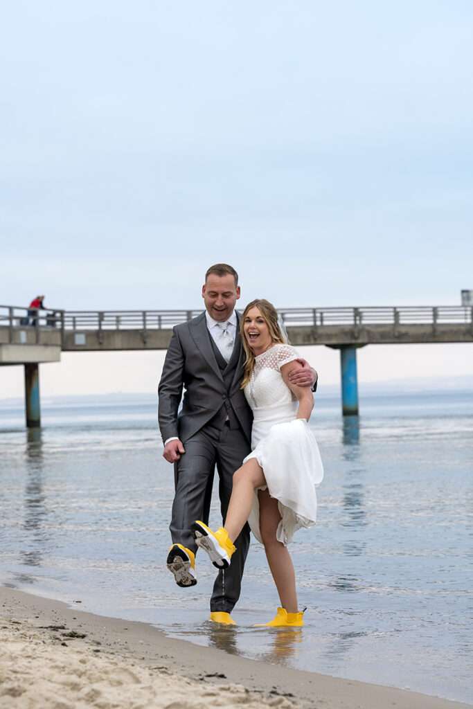 Lustige Brautpaarfotos von Hochzeitsfotograf Mazelle am Strand von Sellin an der Seebrücke auf der Insel Rügen mit Mazelle Photography Fotostudio®