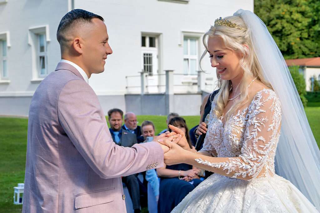 Der Ringtausch ist einer der bewegendsten Augenblicke einer Trauung – festgehalten im Schloss Hohendorf von Mazelle Photography Fotostudio®. Mit viel Liebe zum Detail und einem Gespür für authentische Emotionen dokumentieren wir den Moment, in dem das Brautpaar seine ewige Verbundenheit besiegelt. Die historische Kulisse des Schlosses verleiht den Hochzeitsfotos eine einzigartige Eleganz und schafft eine Atmosphäre voller Romantik und zeitloser Schönheit. Unsere Hochzeitsfotografie verbindet moderne Bildsprache mit klassischer Ästhetik und macht diesen besonderen Augenblick unvergesslich.